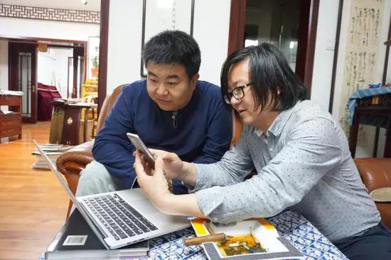 执行主编卢新元与《美术报》首席记者蔡树农讨论稿件